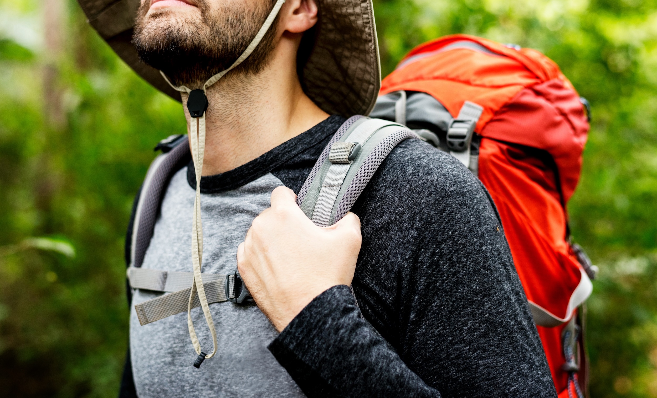 A camper shouldering a packed backpack on a forest trail