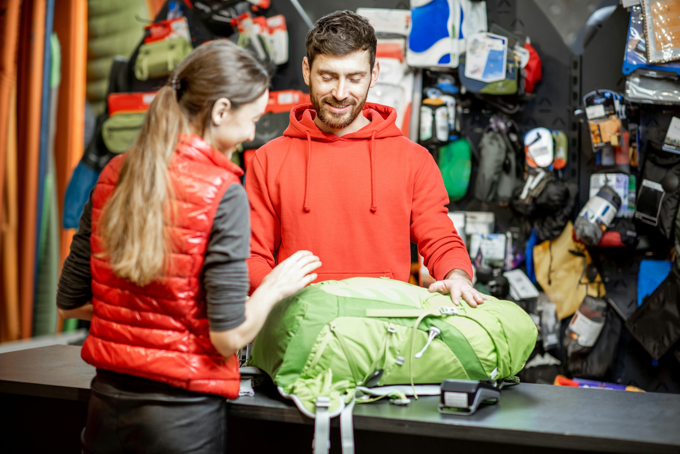 An outfitter staff member and a customer looking over a backpack at the shop counter